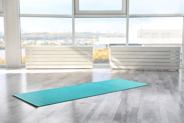 Unrolled light blue yoga mat on floor in room — Stock Photo, Image