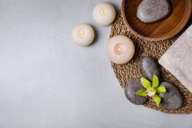 Gri masa üzerinde spa taşları ve yanan mumlarla düz kompozisyon, metin için boşluk