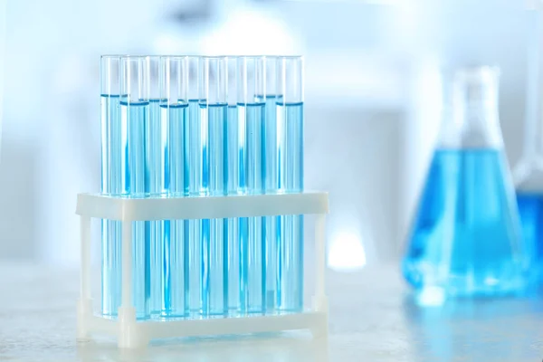 Testbuizen met lichtblauwe vloeistof op tafel in het laboratorium — Stockfoto