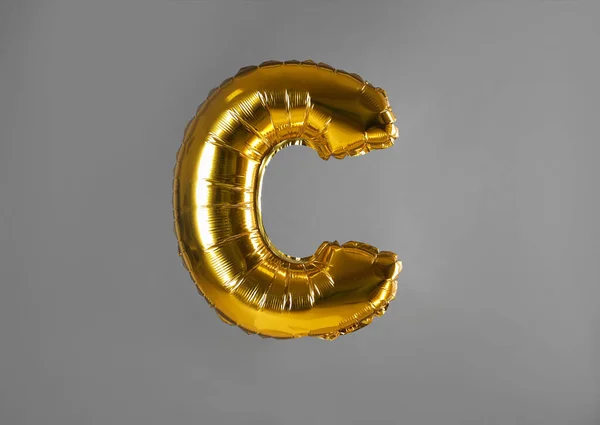 Ballon de lettre C doré sur fond gris — Photo
