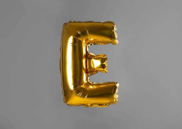 Golden letter E balloon on grey background — Stock Photo, Image