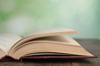 Tahta masa üzerine açık kitap bulanık yeşil arkaplan, yakın plan