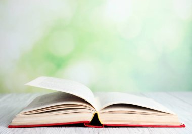 Bulanık yeşil arka plana karşı beyaz ahşap masa üzerine açık bir kitap. Metin için boşluk