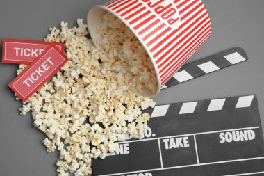 Patlamış mısır ve sinema biletleriyle gri arka planda düz kompozisyon