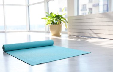 Odada yerde açık mavi yoga minderi var.