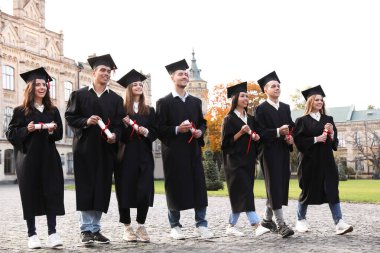 Açık havada diplomalı mutlu öğrenciler. Mezuniyet töreni