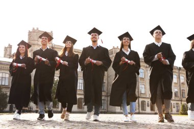 Açık havada diplomalı mutlu öğrenciler. Mezuniyet töreni