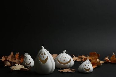 Jack-o-Lantern mum tutucuları ve siyah arka planda düşen yapraklar. Cadılar Bayramı Dekorasyonu