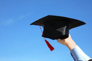 Mezuniyet şapkası ve mavi gökyüzü olan öğrenci, yakın plan.