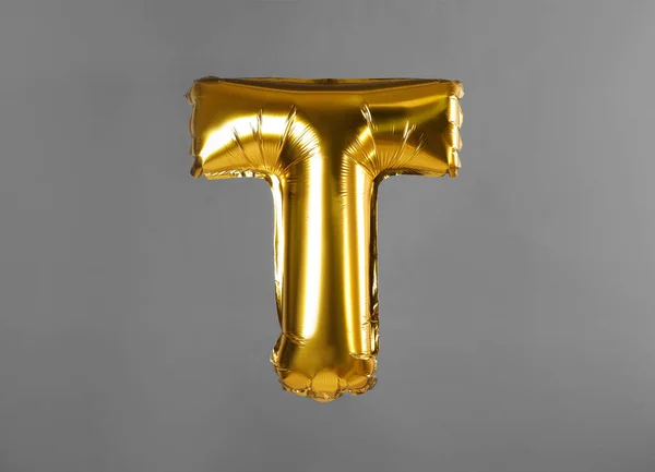 Golden letter T balloon on grey background — Stock Photo, Image