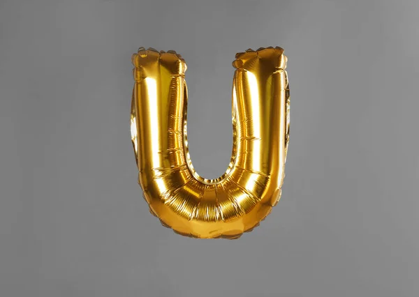 บอลลูนตัวอักษรทอง U บนพื้นหลังสีเทา — ภาพถ่ายสต็อก