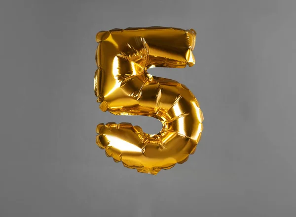 Zlatý balón číslo pět na šedém pozadí — Stock fotografie