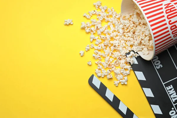 Klapptafel und Popcorn auf gelbem Hintergrund, flache Lage mit Platz für Text. Kinosnack — Stockfoto