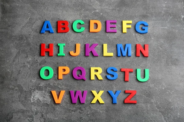 Letras magnéticas coloridas sobre fundo de pedra cinza, flat lay. Ordem alfabética — Fotografia de Stock