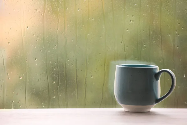 Cup of drink on windowsill, space for text. Rainy weather — Stockfoto