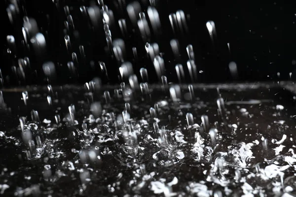 Heavy rain falling down on ground against dark background, closeup — Stock Photo, Image