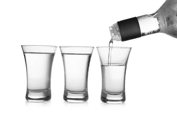 Pouring cold vodka into shot glass on white background — ストック写真