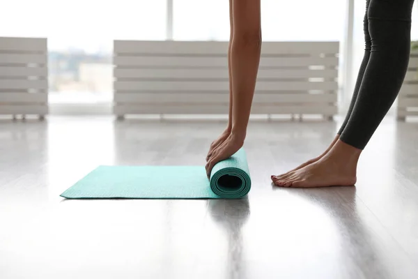 Femme déroulant tapis dans le studio de yoga, gros plan — Photo