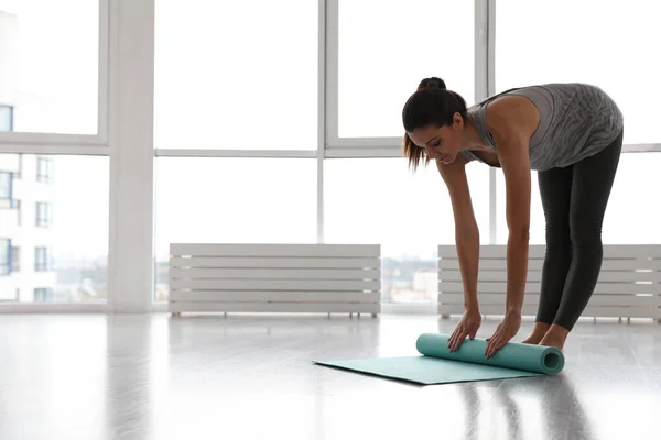 Alfombra desenrollable de mujer joven en estudio de yoga —  Fotos de Stock