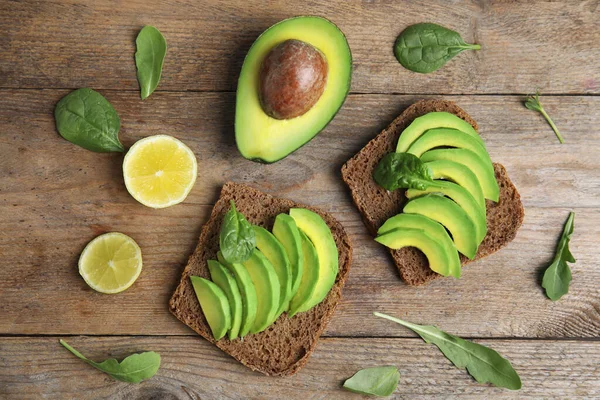 Platte lay compositie met avocado toastjes op houten tafel — Stockfoto