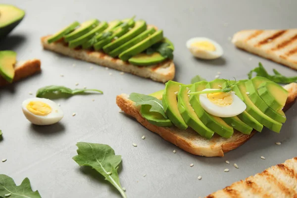 Tasty avocado toasts on light grey table — Stockfoto