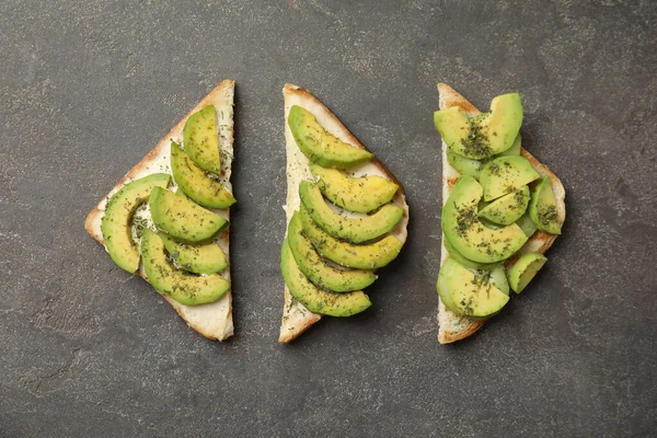 Smaklig avokado rostat bröd på grått bord, platt låg — Stockfoto