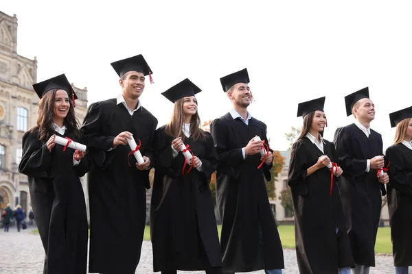 Estudantes felizes com diplomas ao ar livre. Cerimónia de graduação — Fotografia de Stock