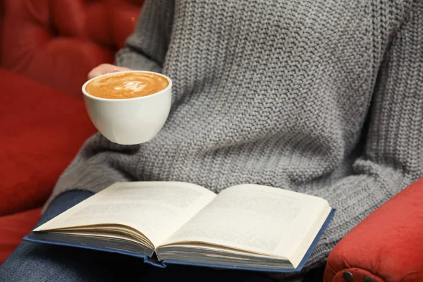 Mujer con taza de café libro de lectura en el sofá, primer plano — Foto de Stock