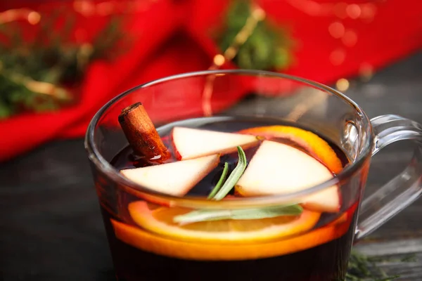 Νόστιμο ζεστό κρασί με μπαχαρικά σε γυάλινο κύπελλο στο ξύλινο τραπέζι, closeup — Φωτογραφία Αρχείου
