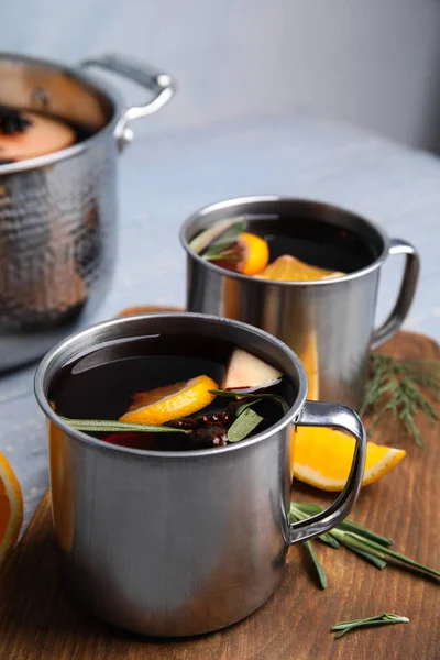 Vinho quente saboroso com especiarias em canecas na mesa de madeira — Fotografia de Stock