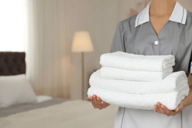 Otel odasında temiz havlu yığını olan oda hizmetçisi, yakın çekim. Metin için alan