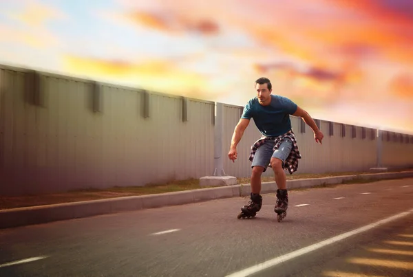 Handsome young man roller skating outdoors. Recreational activity