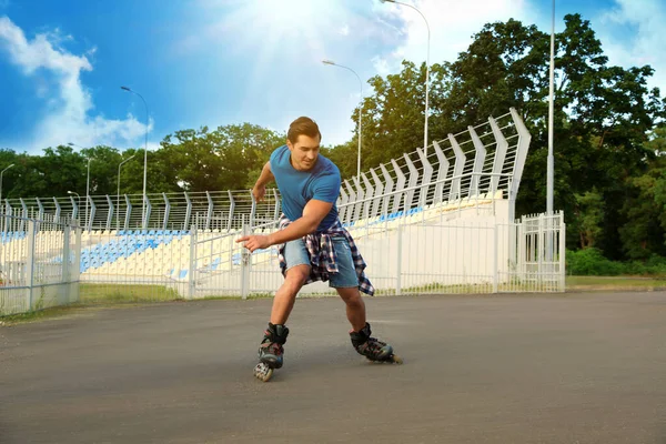 Handsome young man roller skating outdoors. Recreational activity