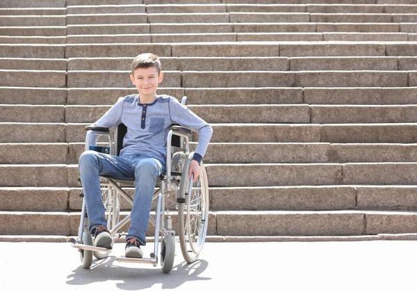 Předdospívající chlapec na invalidním vozíku na kamenných schodech venku — Stock fotografie