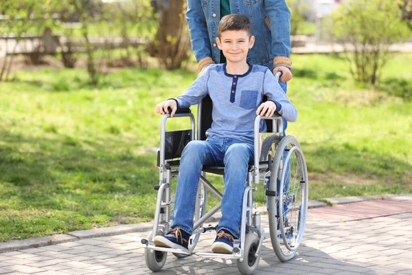 Niño preadolescente en silla de ruedas con su padre en el parque en el día soleado — Foto de Stock