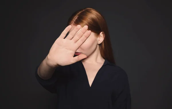 Mujer joven haciendo gesto de parada contra el fondo oscuro, enfoque en la mano —  Fotos de Stock