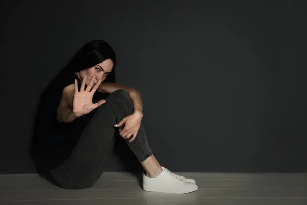 Jovem mulher fazendo parar gesto enquanto sentado no chão perto da parede cinza. Espaço para texto — Fotografia de Stock