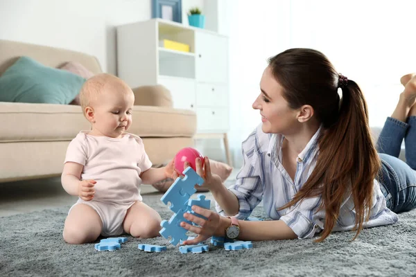 Feliz madre jugando con el pequeño bebé en el suelo en interiores —  Fotos de Stock