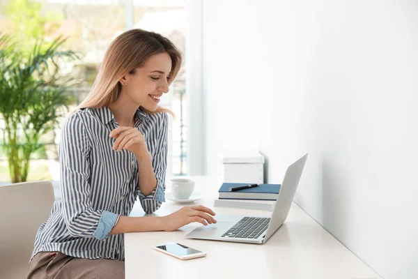 Joven mujer de negocios usando portátil en la mesa en la oficina — Foto de Stock