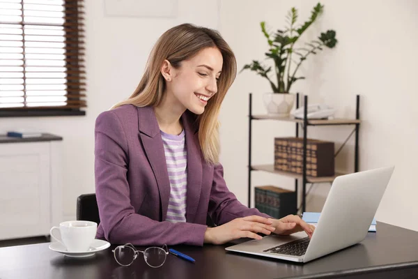 Jonge zakenvrouw met behulp van laptop aan tafel in kantoor — Stockfoto
