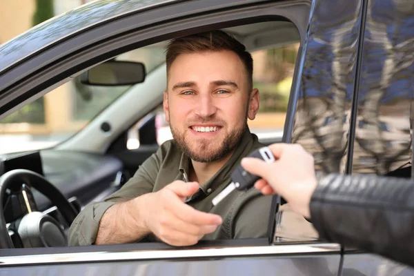 Verkäufer übergibt Autoschlüssel an Kunden im Freien — Stockfoto