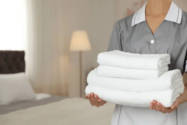 Chambermaid with stack of fresh towels in hotel room, closeup. Space for text — Stock Photo, Image