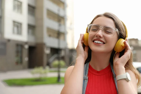 Schöne junge Frau hört Musik mit Kopfhörern an sonnigen Tagen im Freien, Platz für Text — Stockfoto