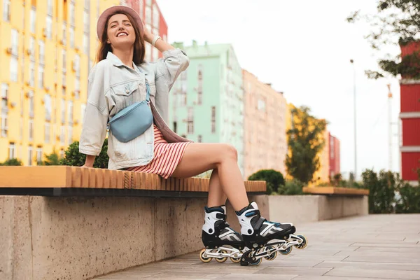 Hermosa joven con patines de ruedas sentada en el banco al aire libre, espacio para el texto —  Fotos de Stock