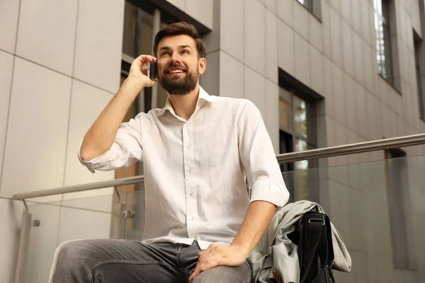 Bonito homem falando ao telefone na cidade moderna — Fotografia de Stock