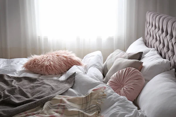 Cómoda cama con cuadros y almohadas en la habitación —  Fotos de Stock