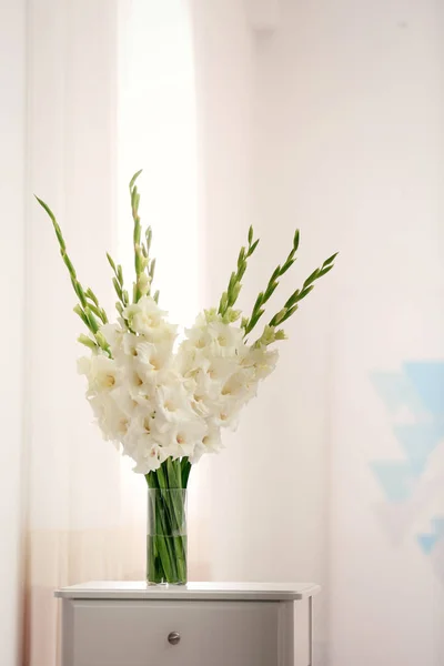 Jarrón con hermosas flores de gladiolo blanco en el cajón en la habitación, espacio para el texto —  Fotos de Stock