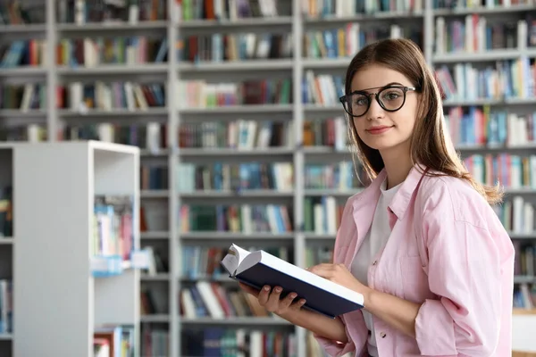 Młoda piękna kobieta z książką w bibliotece — Zdjęcie stockowe
