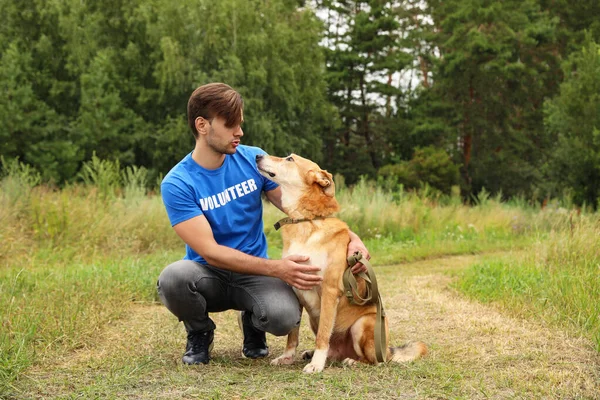 Volontaire masculin avec chien sans abri au refuge pour animaux à l'extérieur — Photo