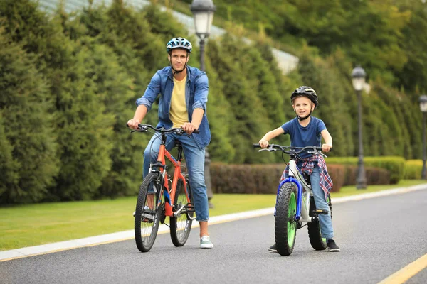 Папа и сын катаются на современных велосипедах на открытом воздухе — стоковое фото